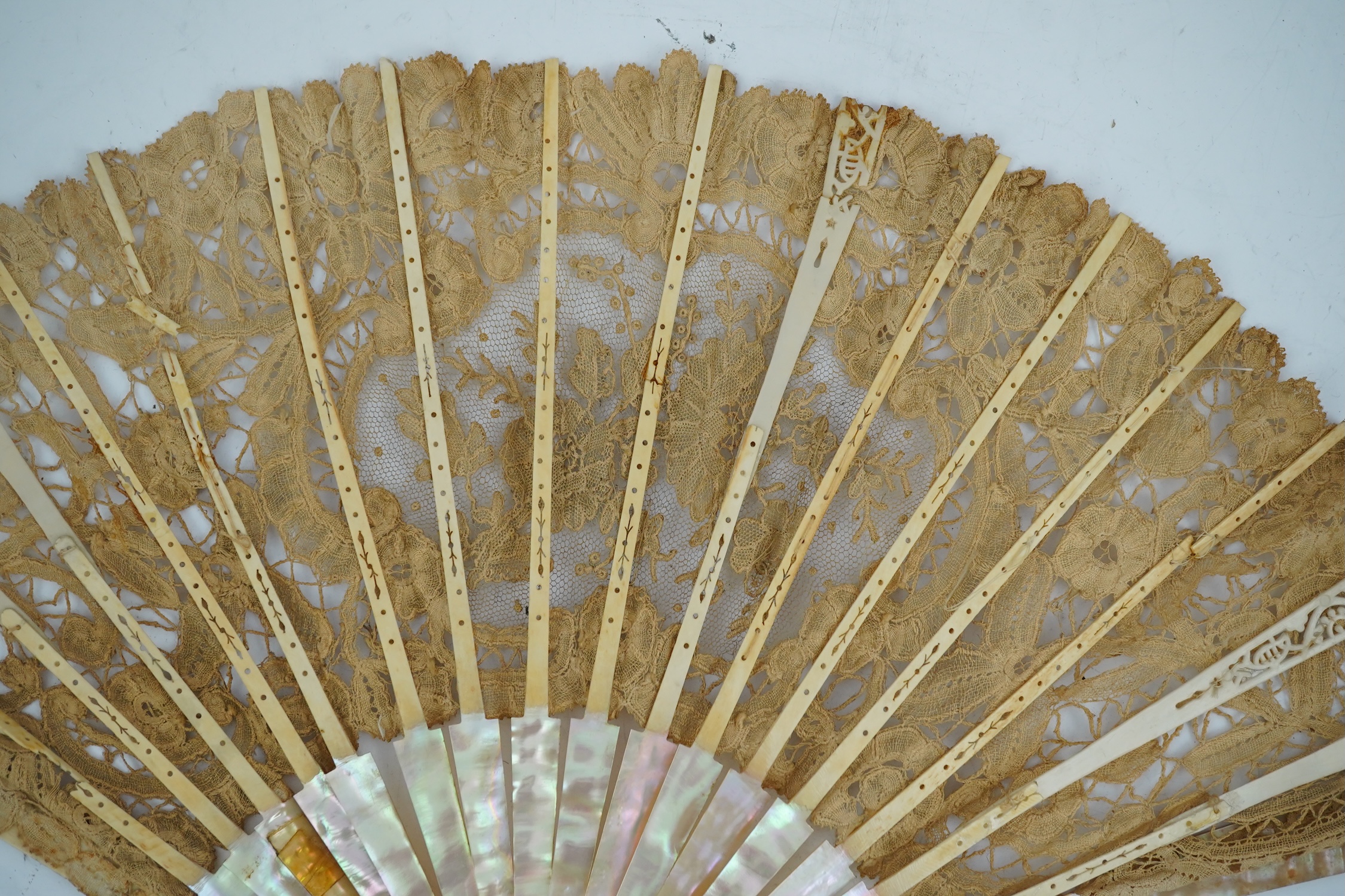 Three novelty fans with a mixed Brussels lace fan and black lace fan, a small language of love in flowers fan, a paper windmill advertising French Café fan, a carved cream Bakelite fan, a black and gilt, lace and sequin